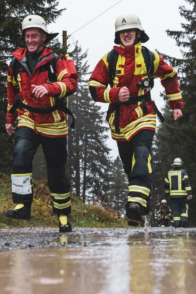 Zwei Teilnehmer in roter Einsatzkleidung neben einer Pfütze.