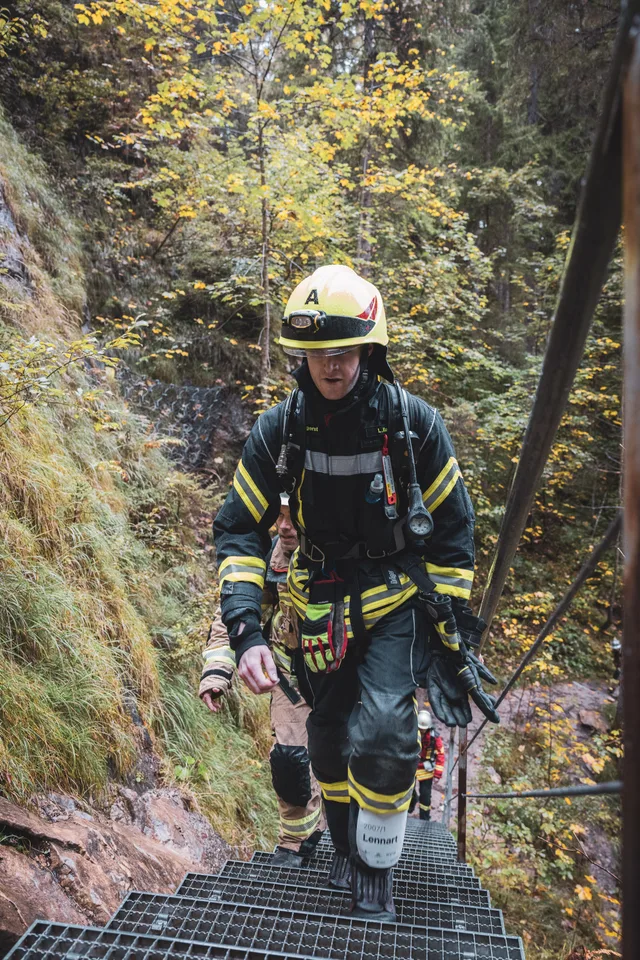 Teilnehmer mit gelbem Helm und dunkler Einsatzkleidung auf der Treppe.