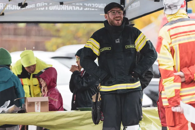 Teilnehmer in Einsatzkleidung bei den Helfern am Tisch.