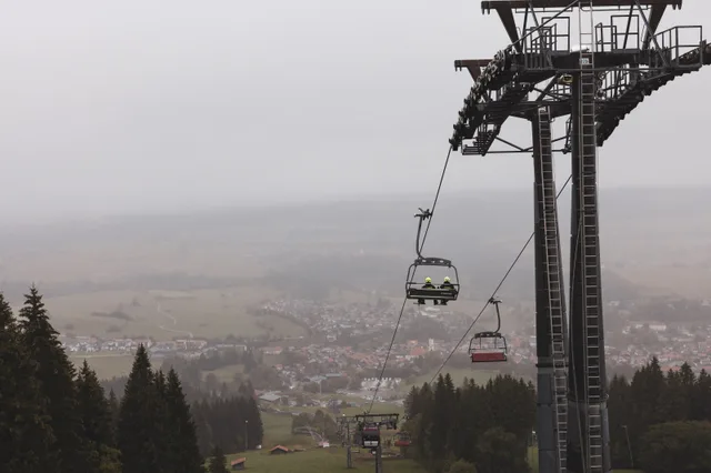 Gondeln und Liftstütze vor dem nebligen Tal.