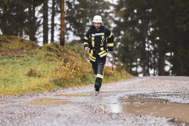 Teilnehmer mit weißem Helm und dunkler Einsatzkleidung läuft ins Ziel.