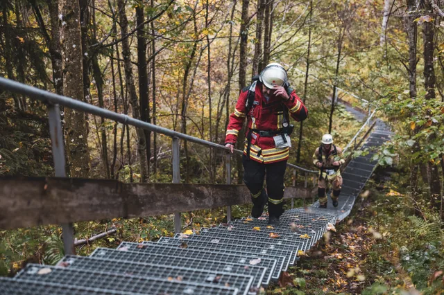 Teilnehmer in roter Einsatzkleidung steigt die lange Metalltreppe hinauf.