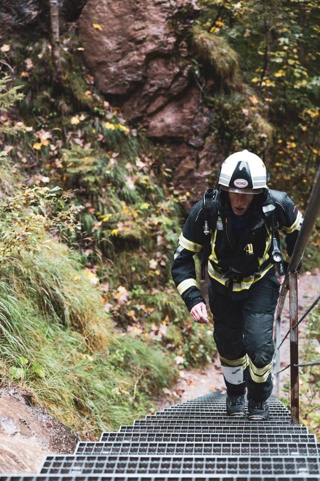Teilnehmer in dunkler Einsatzkleidung steigt eine Metalltreppe hinauf.