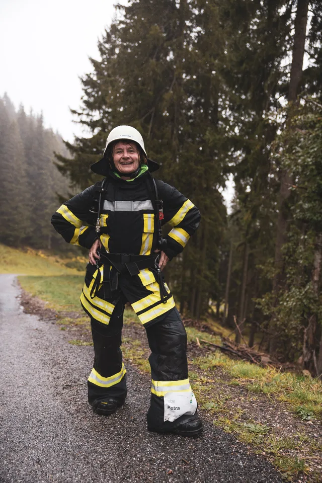 Lachender Teilnehmer in dunkler Einsatzkleidung und weißem Helm auf der Bergstraße.