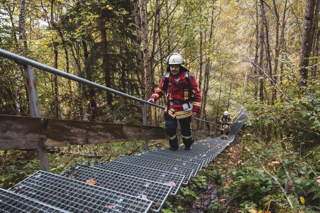 Teilnehmer in roter Einsatzkleidung steigt die lange Metalltreppe hinauf.