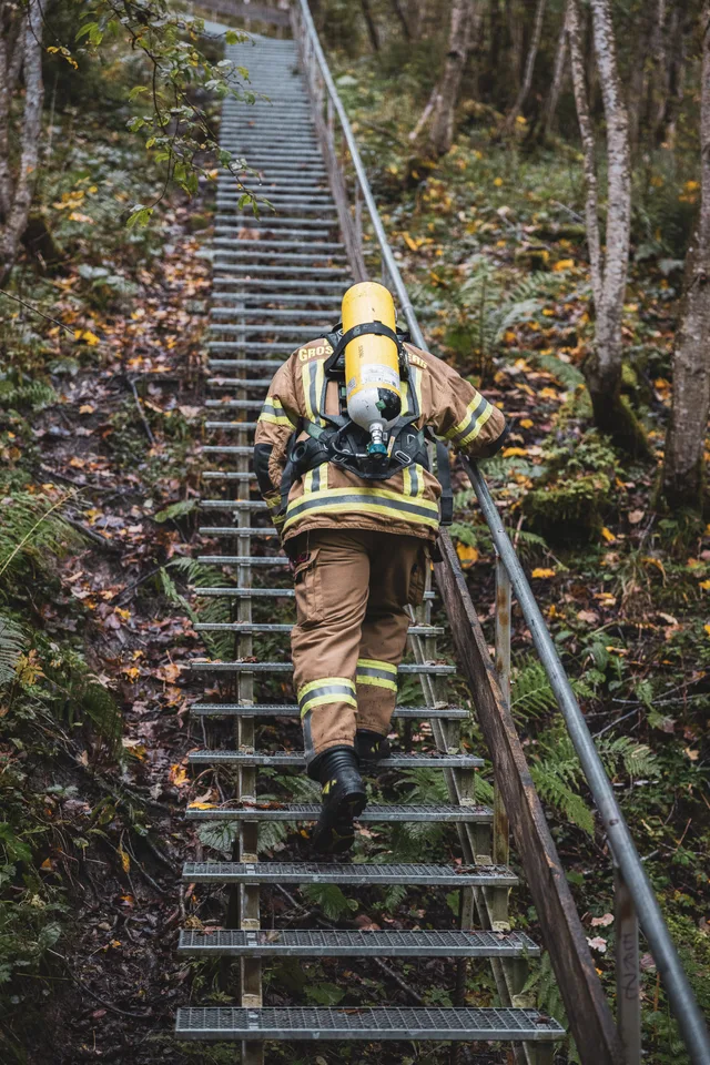 Teilnehmer in beiger Einsatzkleidung steigt eine steile Metalltreppe hinauf.