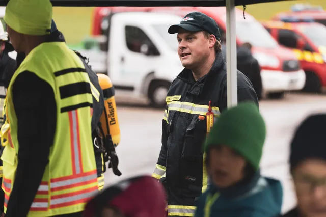 Teilnehmer mit Kappe und dunkler Einsatzjacke im Gespräch.