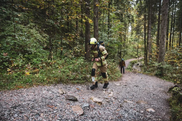Teilnehmer in beiger Einsatzkleidung auf einem felsigen Waldweg.