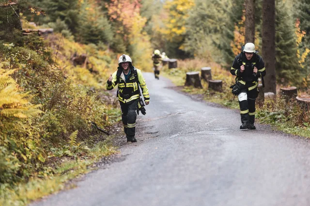 Zwei Teilnehmer in dunkler Einsatzkleidung auf der nassen Bergstraße.