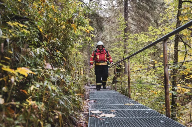 Teilnehmer in roter Einsatzkleidung mit grauem Helm auf den Waldstufen.