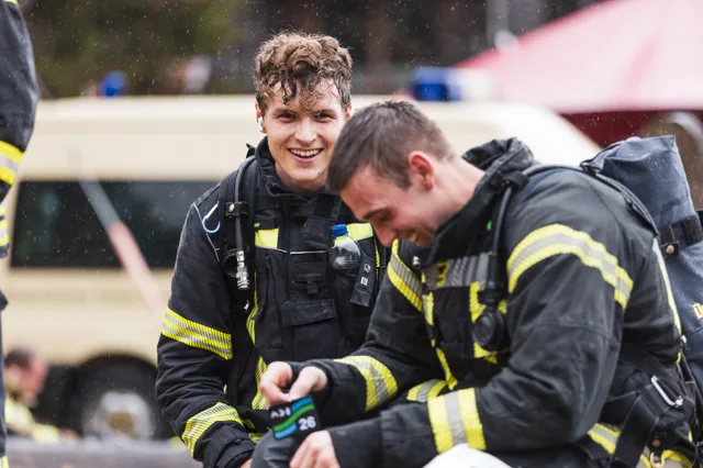 Zwei lachende Teilnehmer ohne Helm sitzen nach dem Zieleinlauf zusammen.