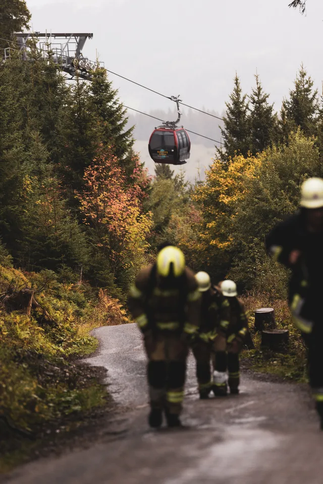 Teilnehmer in schwarzer Einsatzkleidung läuft vor zwei weiteren Teilnehmern bergauf.