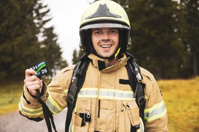 Lachender Teilnehmer mit gelbem Helm zeigt seine Medaille.