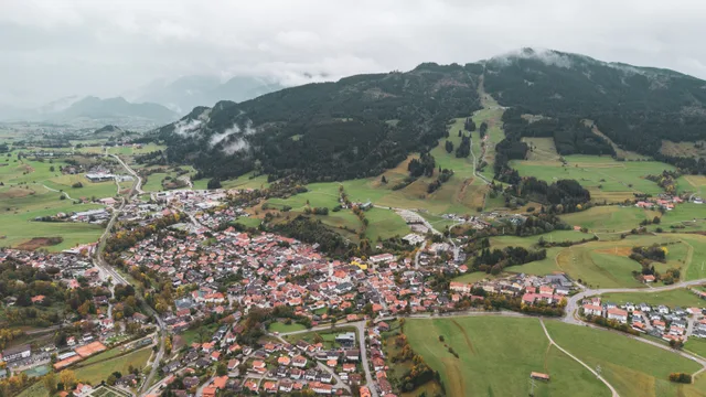 Luftaufnahme von Nesselwang vor den bewaldeten Berghängen.