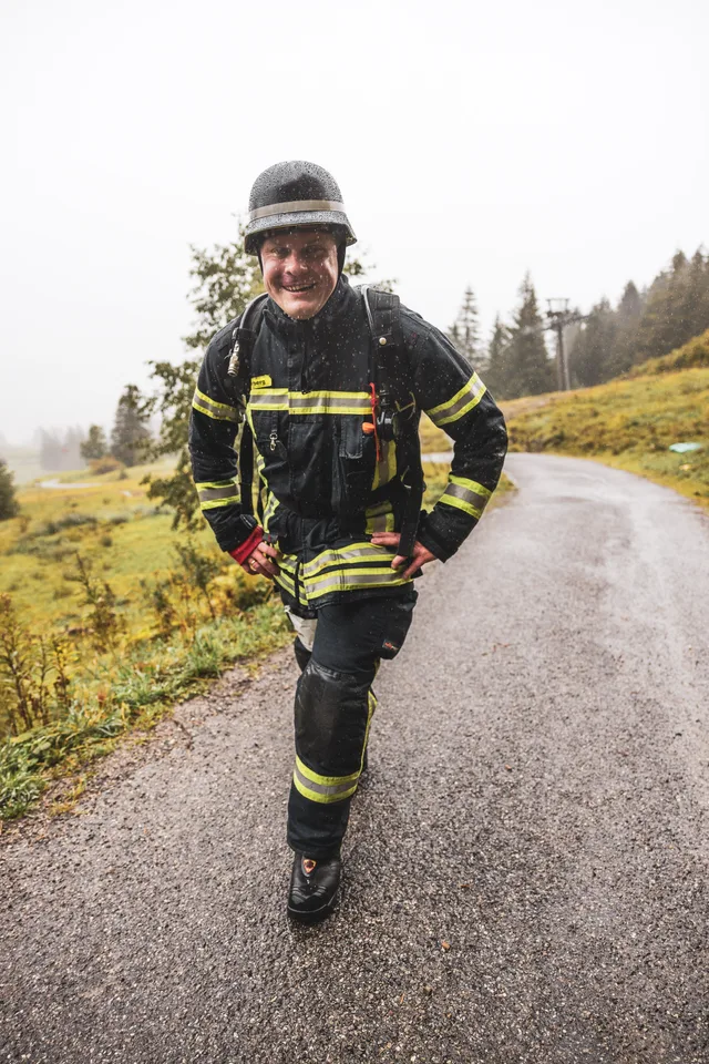 Teilnehmer in schwarzer Einsatzkleidung auf der nassen Bergstraße.