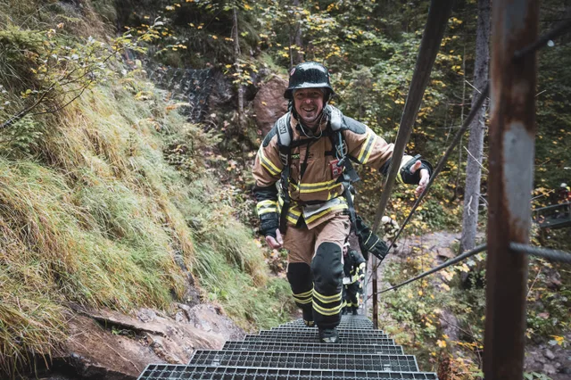 Teilnehmer in beiger Einsatzkleidung mit dunklem Helm auf der Metalltreppe.