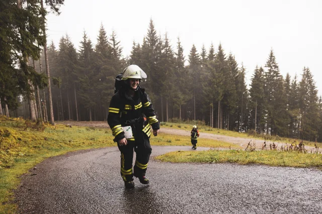 Teilnehmer in schwarzer Einsatzkleidung steigt durch eine Straßenkurve bergauf.