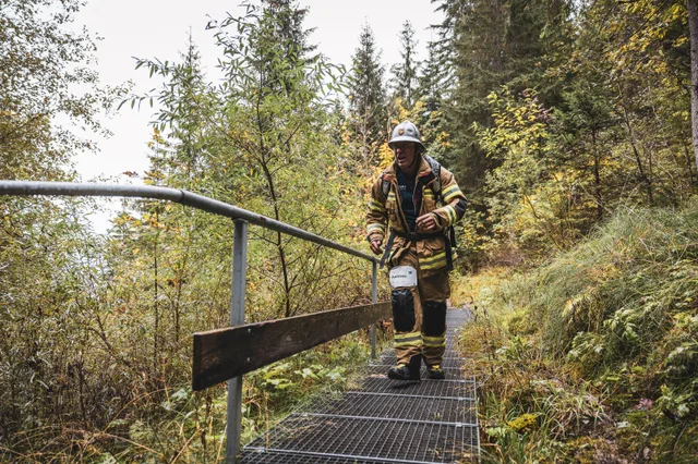 Teilnehmer in beiger Einsatzkleidung auf einem Metallsteg im Herbstwald.