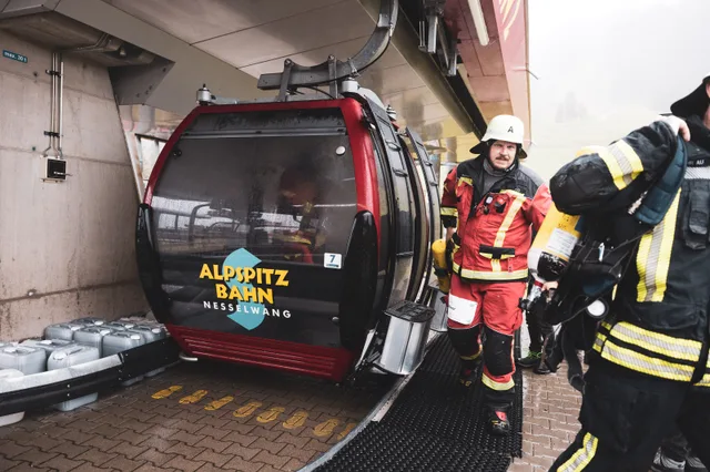 Teilnehmer in Einsatzkleidung neben der Gondel an der Bergstation.