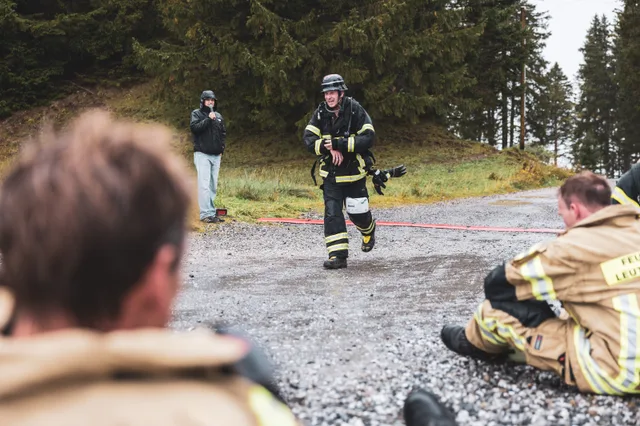 Teilnehmer läuft ins Ziel, während andere auf dem Schotter sitzen.