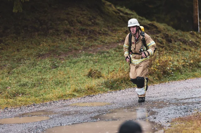 Teilnehmer in beiger Einsatzkleidung läuft zwischen Zuschauern ins Ziel.