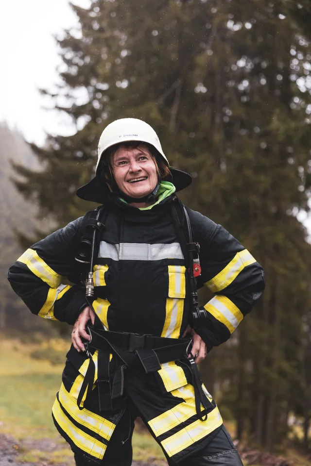 Lachender Teilnehmer in dunkler Einsatzkleidung und weißem Helm auf der Bergstraße.