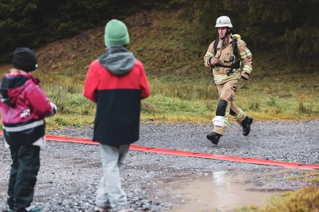 Teilnehmer in beiger Einsatzkleidung läuft zwischen Zuschauern ins Ziel.