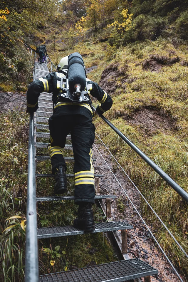Teilnehmer mit Atemschutzgerät von hinten auf der Metalltreppe.