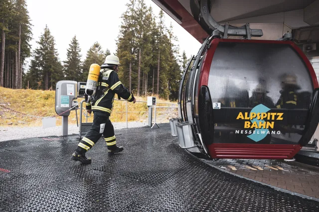 Teilnehmer mit Atemschutzgeräten steigen an der Bergstation in die Gondel.
