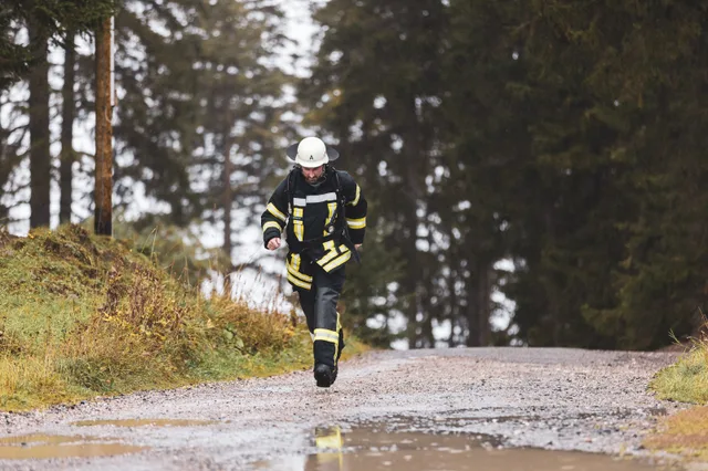 Teilnehmer mit weißem Helm und dunkler Einsatzkleidung läuft ins Ziel.