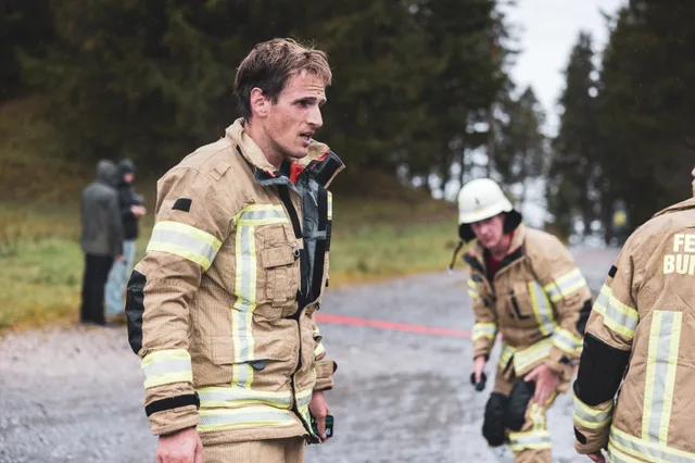 Teilnehmer in beiger Einsatzkleidung stehen mit abgelegter Ausrüstung im Zielbereich.