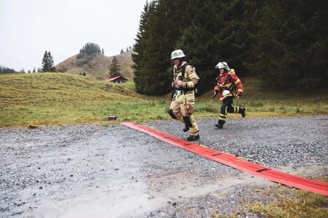 Zwei Teilnehmer in beiger und roter Einsatzkleidung erreichen die Zielmarkierung.