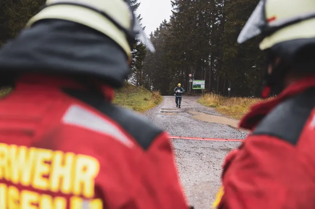 Blick zwischen Teilnehmern in roten Jacken auf einen Zieleinlauf.