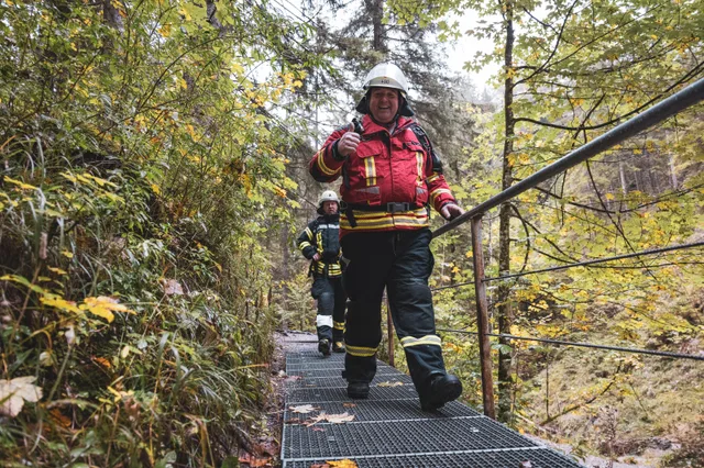 Teilnehmer in roter Einsatzkleidung mit grauem Helm auf den Waldstufen.