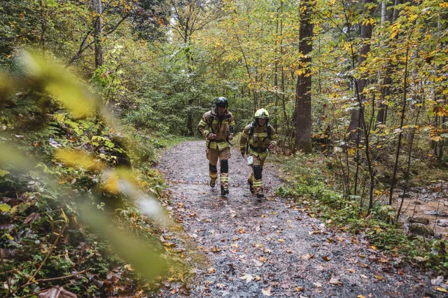 Zwei Teilnehmer in beiger Einsatzkleidung auf einem Waldweg.
