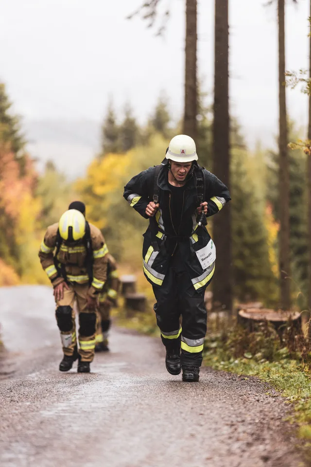 Teilnehmer in schwarzer Einsatzkleidung läuft vor zwei weiteren Teilnehmern bergauf.