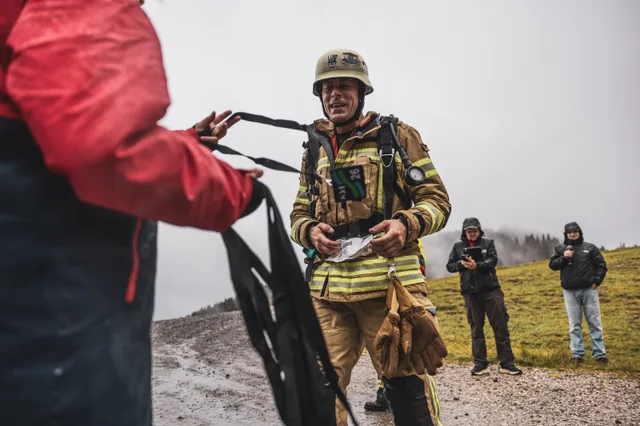 Ein Feuerwehrteilnehmer erhält im regennassen Zielbereich eine Medaille.