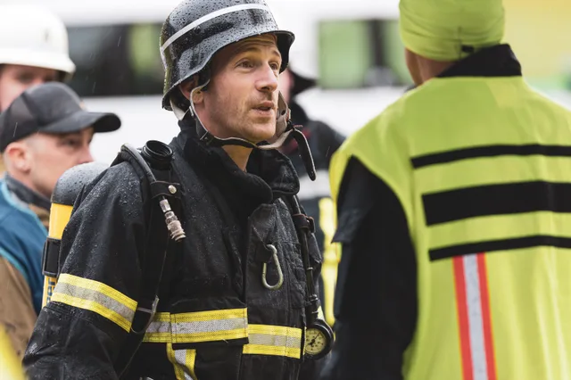 Teilnehmer mit schwarzem Helm im Gespräch mit einem Helfer in Warnweste.