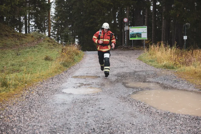 Teilnehmer in roter Einsatzkleidung läuft mit ausgebreiteten Armen ins Ziel.