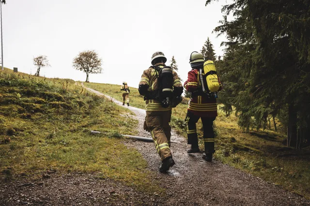 Zwei Teilnehmer verlassen den Wald und gehen einen nassen Weg bergauf.