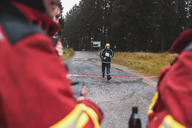Blick zwischen Teilnehmern in roten Jacken auf einen Zieleinlauf.