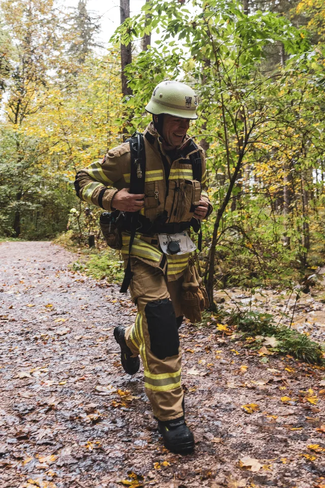 Teilnehmer mit weißem Helm und beiger Einsatzkleidung auf dem Waldweg.