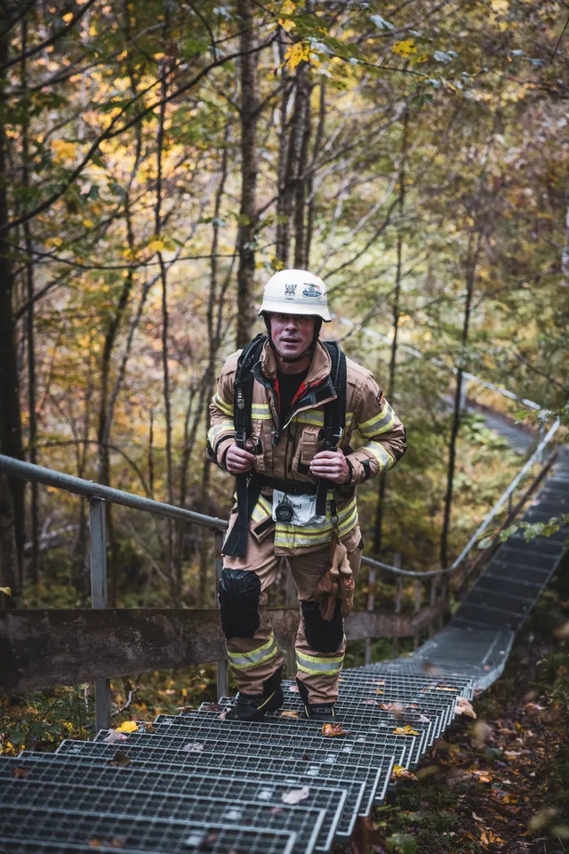 Teilnehmer in beiger Einsatzkleidung auf der langen Treppe im Herbstwald.