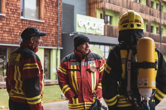 Gruppe in roter und schwarzer Einsatzkleidung vor dem Explorer Hotel.