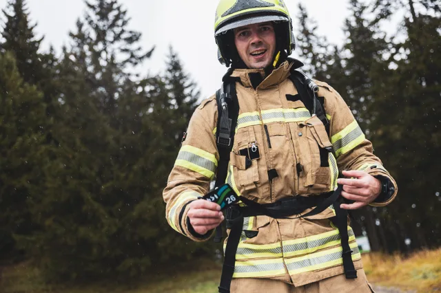 Lachender Teilnehmer mit gelbem Helm zeigt seine Medaille.