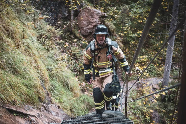 Teilnehmer in beiger Einsatzkleidung mit dunklem Helm auf der Metalltreppe.