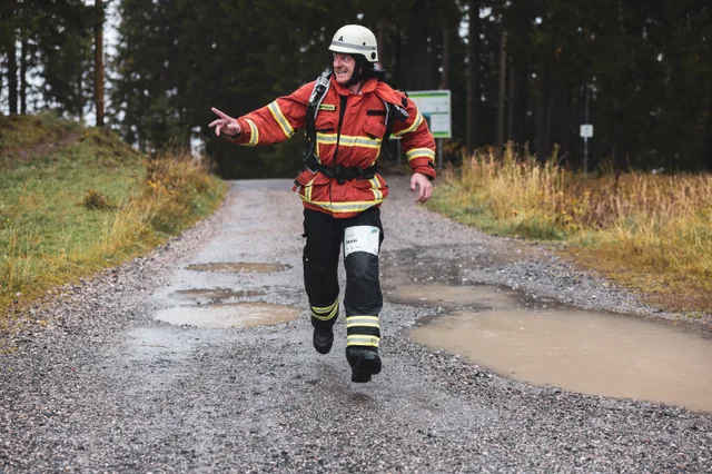 Teilnehmer in roter Einsatzkleidung läuft mit ausgebreiteten Armen ins Ziel.