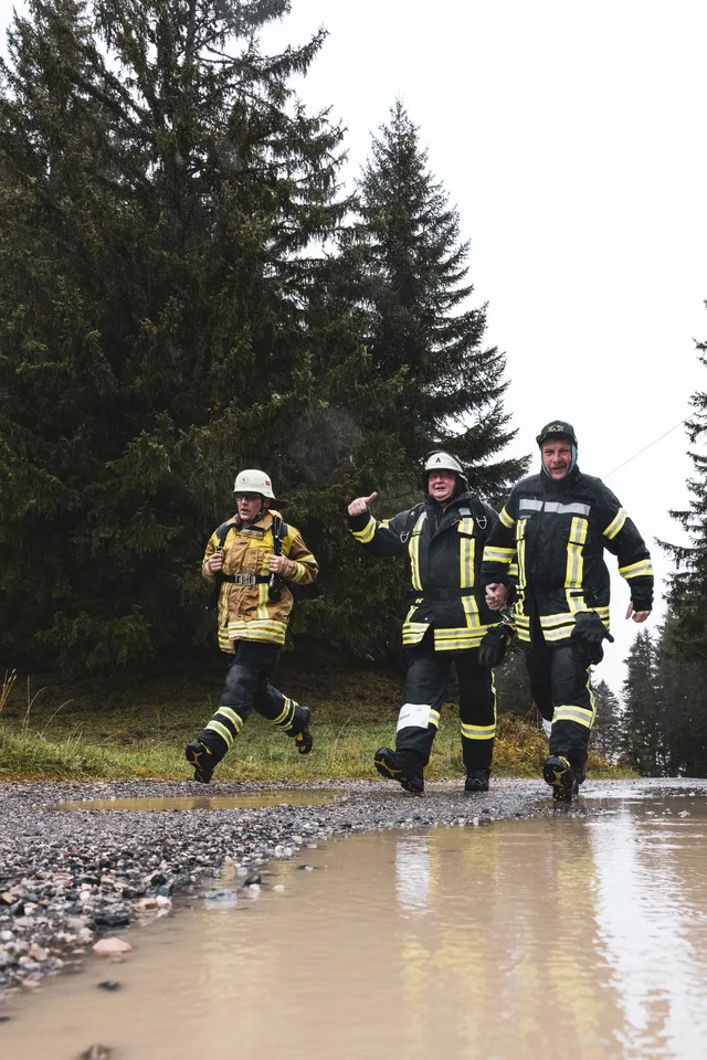 Gruppe in Einsatzkleidung läuft an einer großen Pfütze entlang.