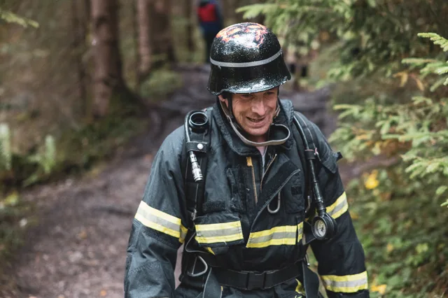 Teilnehmer in schwarzer Einsatzkleidung und dunklem Helm im Wald.