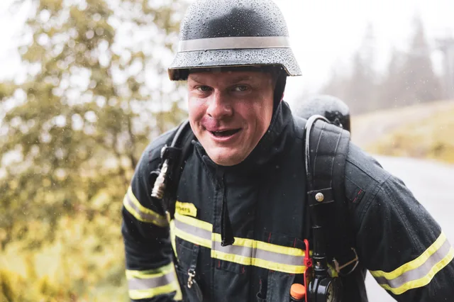 Nahansicht eines Teilnehmers mit schwarzem Helm beim Aufstieg im Regen.